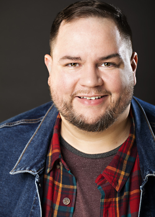 Josh Boyd headshot, smiling, denim jacket over a plaid shirt